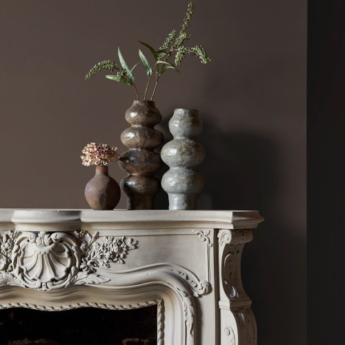 Fireplace wall painted in Abigail Ahern Dewdrop Moss with cosy, layered textures