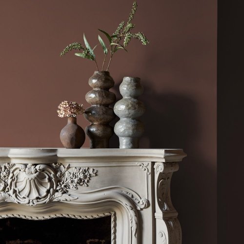 Fireplace wall painted in Abigail Ahern Oaken Cask with cosy, layered décor