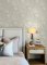 A Street Prints Vita Taupe Wallpaper shown in a bedroom with earthy tropical leaf and botanical style