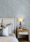 A Street Prints Vita Blue Wallpaper styled in a serene bedroom with pale wood furniture and leafy accents