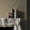 Fireplace wall painted in Abigail Ahern Moody Sage with warm, textural décor